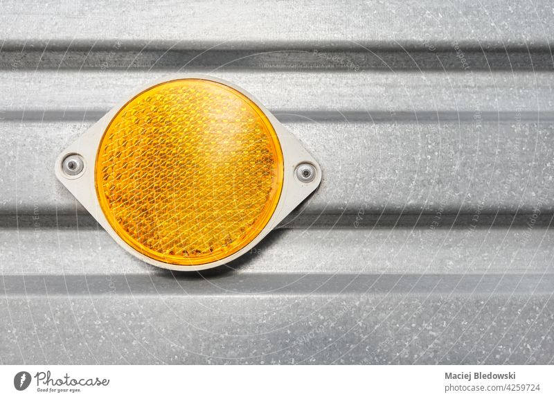 Nahaufnahme eines runden gelben Kunststoffreflektors, der an einer Anhänger-Wellblechwand befestigt ist. Reflektor reflektierend orange Sicherheit Metall Wand