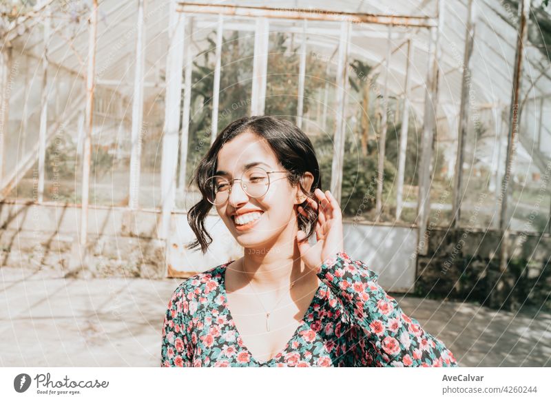 Junge marokkanische Frau lächelnd zur Kamera in herbstlichen und entsättigten Farben mit Kopie Raum und moderne Kleidung lockig Hipster Teenager Lächeln