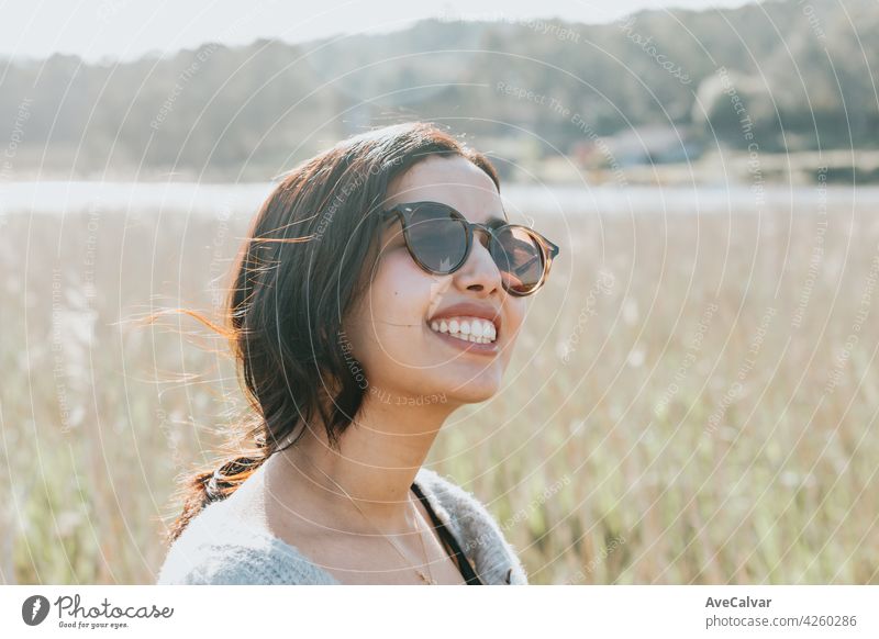 Frau mit Sonnenbrille lächelnd in die Kamera, während auf dem Land Hof während einer super sonnigen Tag mit Kopie Raum und Lifestyle Schuss Person sorgenfrei