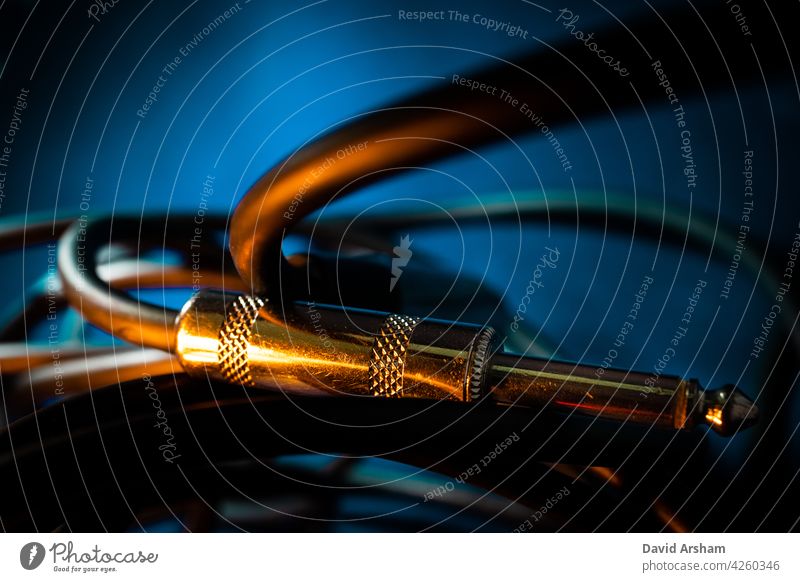 Makro-Nahaufnahme von Metall Viertel-Zoll-Instrument Kabelstecker horizontal auf Kabel vor Teal Hintergrund mit Orange Beleuchtung Viertelzoll Wagenheber