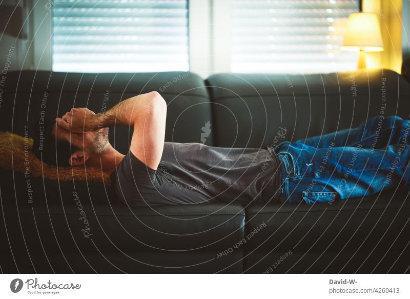 Verkatert - Mann liegt mit Kopfschmerzen auf dem Sofa liegen verkatert unwohl krank Krankheit Virus
