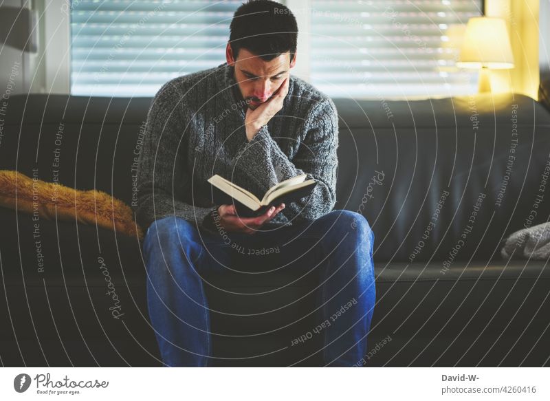 Mann vertieft in ein Buch lesen Sofa Bildung Roman Leser Literatur lernen konzentriert Wissen zu Hause sitzen