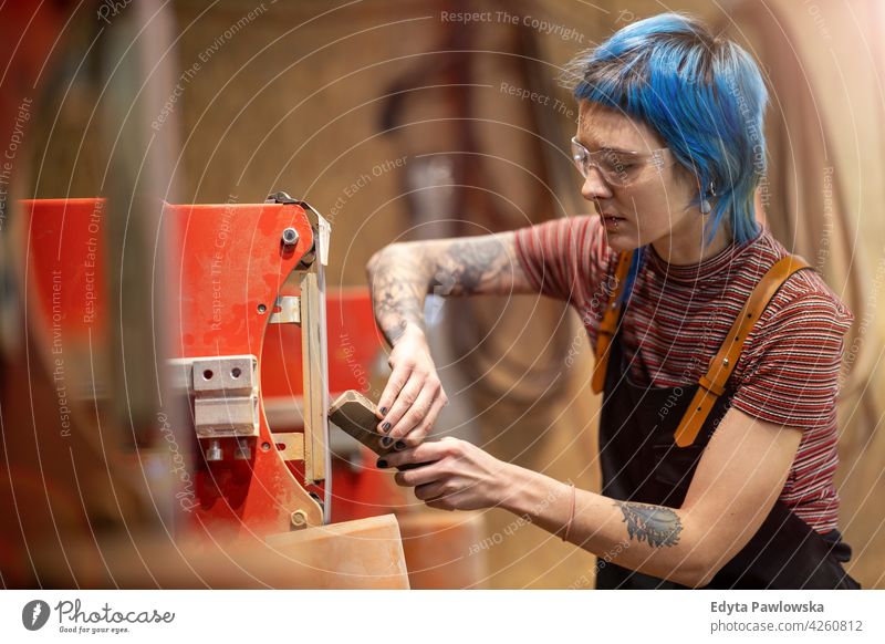 Junge Handwerkerin bei ihrer Arbeit diy Hipster Behaarung Tattoos Frau Besitzer Beruf Dienst Werkstatt Kleinunternehmen Mitarbeiter arbeiten Arbeitsplatz