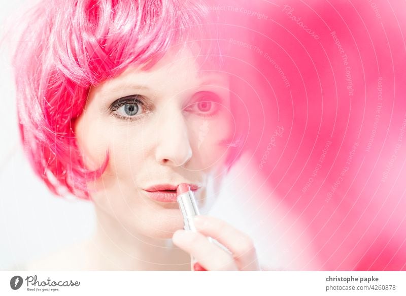 Frau mit pinker Perücke trägt Lippenstift auf Schminken Haare & Frisuren feminin Gesicht Spiegel Spiegelbild Kosmetik Junge Frau schön Mund Erwachsene Mensch