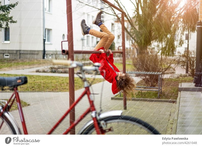 Mädchen mit Spaß im Freien in städtischen Bereich Spaß haben Fahrrad Metall Bar Kleiderbügel Genuss spielerisch Teenager Behaarung hängen nach unten