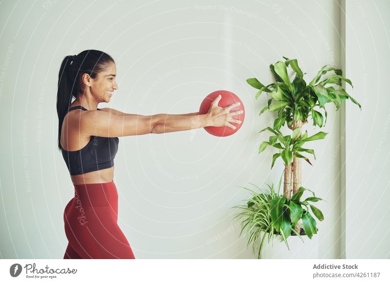 Lächelnde ethnische Sportlerin beim Training mit einem Fit-Ball ausdehnen Passform-Ball Übung üben Inhalt Raum Frau Vitalität Athlet Fitness Energie genießen