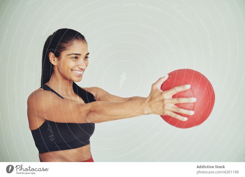 Lächelnde ethnische Sportlerin beim Training mit einem Fit-Ball ausdehnen Passform-Ball Übung üben Inhalt Raum Frau Vitalität Athlet Fitness Energie genießen