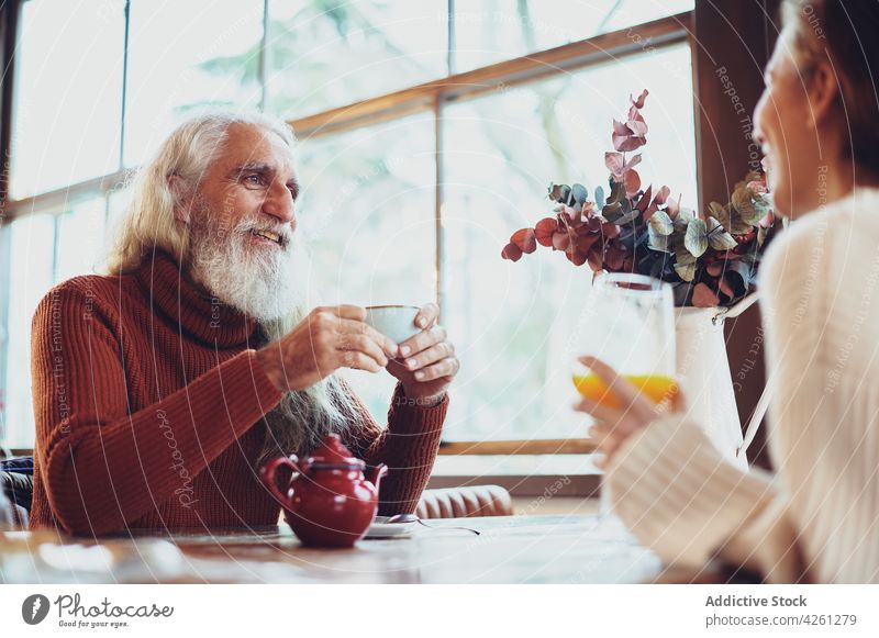 Fröhlicher Mann im Gespräch mit nicht erkennbarem Partner in einem Cafe sprechen Freund Tee Heißgetränk freundlich Zeit verbringen Glück Tisch Café