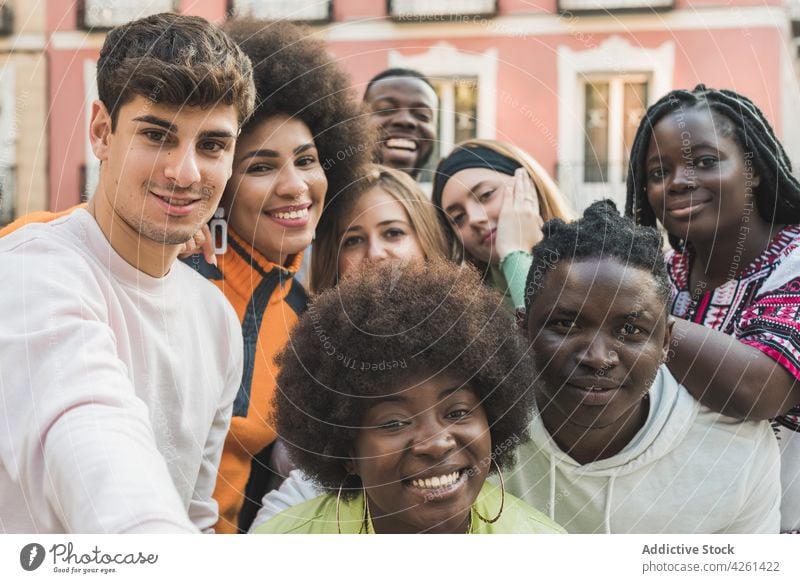 Glückliche multiethnische Freunde schauen in die Kamera, während sie in der Stadt stehen Lächeln Straße Männer Frauen Gerät Inhalt froh Spaß haben Zusammensein