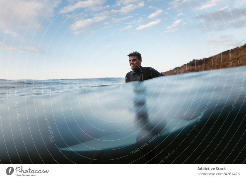 Lächelnder Sportler beim Surfen im Meer unter bewölktem Himmel Surfer Surfbrett Reittier Natur Mann wolkig MEER Wasser wellig Rippeln Wellness Vitalität endlos