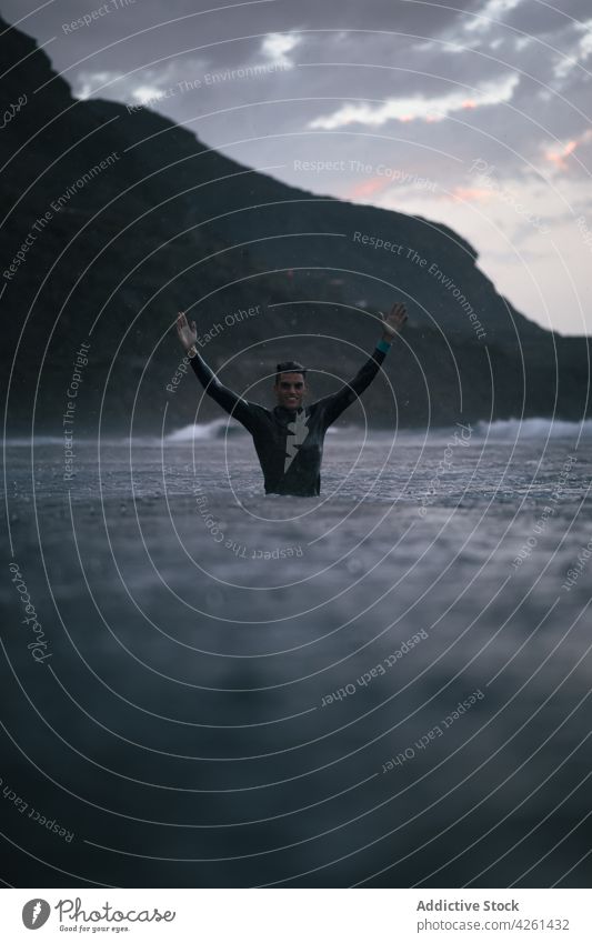 Sportler im Meer gegen den Bergrücken bei Sonnenuntergang Athlet MEER Arme hochgezogen Berge u. Gebirge professionell Natur Hochland Mann Lächeln genießen