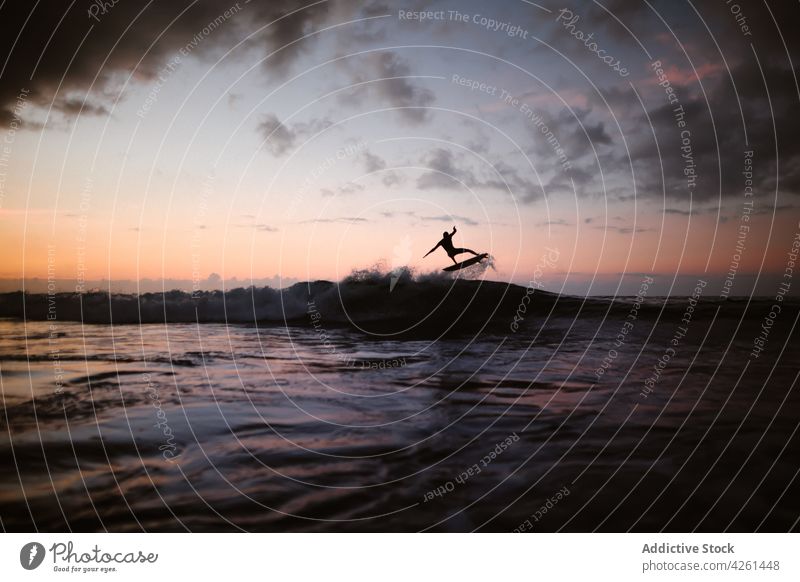 Unbekannter Sportler übt Surfen auf einer Welle bei Sonnenuntergang Surfer üben extrem winken Energie MEER Mann Silhouette dynamisch fließen schnell Aktivität