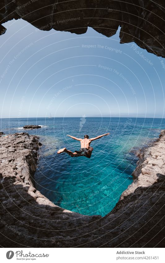 Rückenansicht eines anonymen Mannes, der über das Meer springt springen Höhle Natur Hochland Golfloch Himmel Aktivität auflehnen Reittier rau endlos Horizont