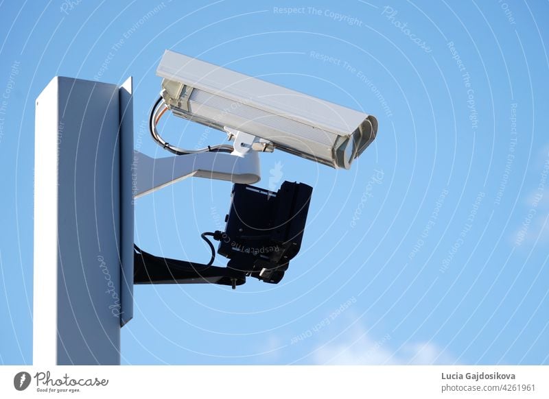 Industrielle Sicherheits-CCTV-Kamera auf Metallzaun installiert. Die Kamera schützt das Industriegelände. Blauer Himmel ist auf dem Hintergrund. Gebäude