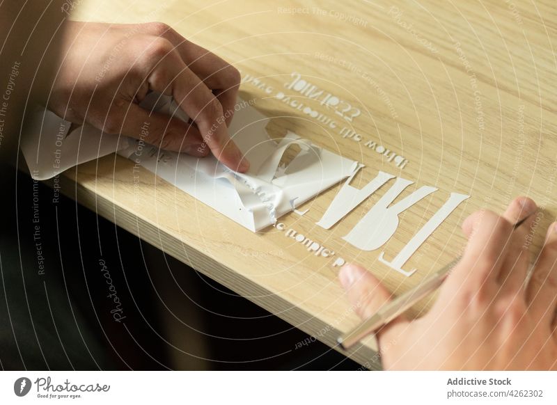 Unkenntlich gemachte Person, die ausgeschnittene Buchstaben auf transparentes Klebeband überträgt transferieren Brief Ausschnitt kreieren Papier Prozess