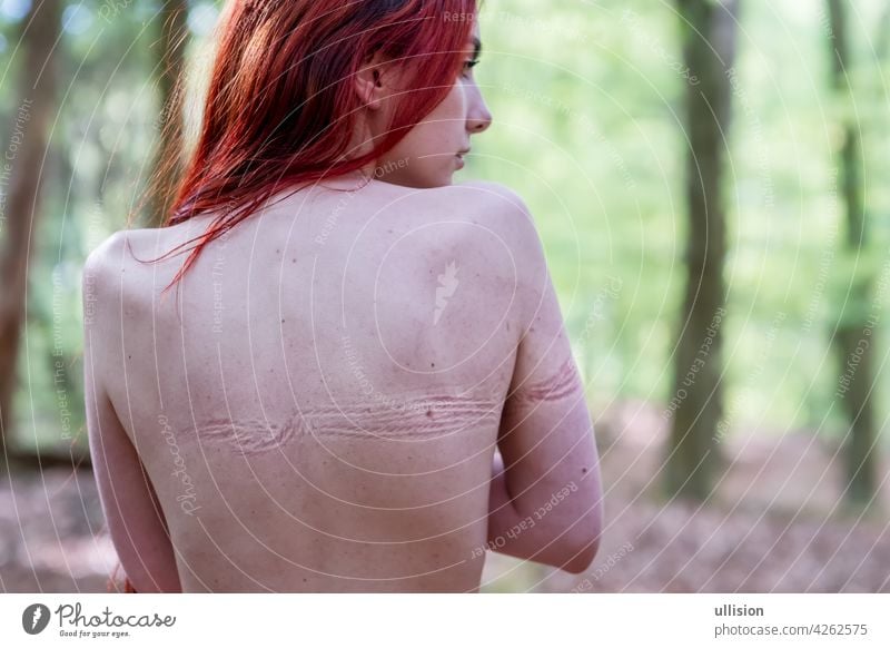 Rücken der jungen schönen sexy Frau mit langen Haaren im Wald mit Abdrücken von gebundenen Seil von Bondage auf nackter Haut Aufdrucke Fesselspiel Missbrauch