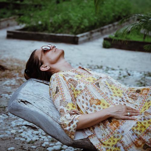 Frau im Kleid liegt entspannt auf einer Holzliege in einem Garten schön liegen entspannen Liege Urlaub chillen relaxen Sommer Reise Gemüsebeet Pflanzen grün