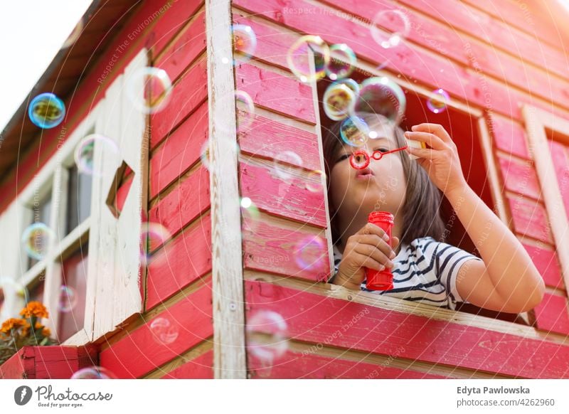 Junge bläst Seifenblasen in einem hölzernen Spielhaus Holz rot Schweden Haus Baum Baumhaus Sommer im Freien Abenteuer spielerisch echte Menschen einfaches Leben