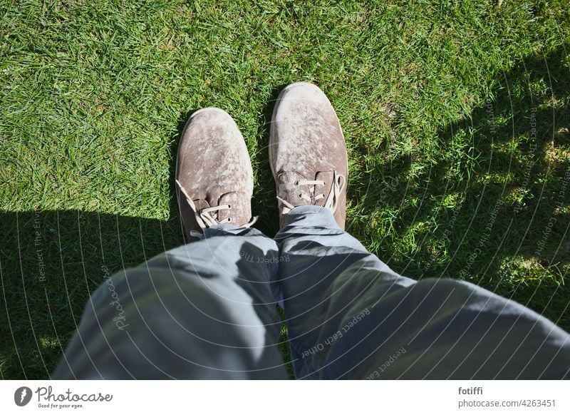52 | große Füße in braunen, lehmigen Schuhen Fuß Lehm verschmiert Botten Schmierbotten Mensch Beine Rasen Gras Vogelperspektive Schatten Außenaufnahme Wiese