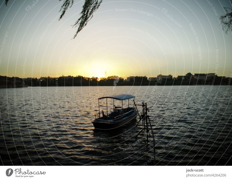 Abendsonne über dem See Beihai mit einem kleinen Boot Natur Landschaft Seeufer Erholung ruhig Idylle Sommer Wolkenloser Himmel Schönes Wetter Sonnenlicht Umwelt