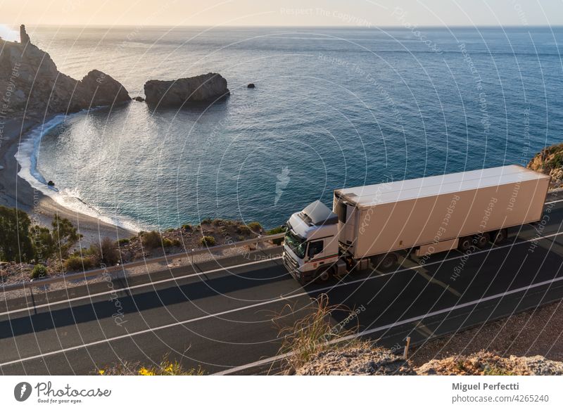 Lkw mit Kühlsattelauflieger fährt entlang einer Straße am Meer mit einem Strand im Hintergrund. gekühlt Lastwagen Verkehr Anhänger Außenaufnahme Landschaft
