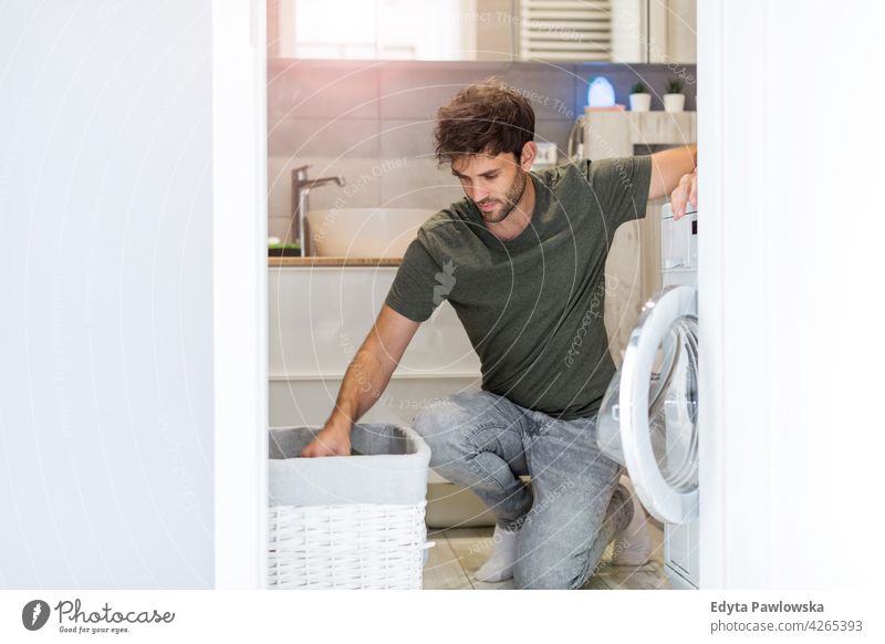 Mann belädt Waschmaschine heimisch lässig heimwärts im Innenbereich Appartement modern Haus männlich Menschen jung junger Erwachsener Kaukasier eine Person