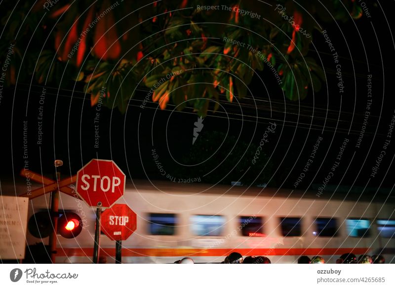 Bahnübergang mit vorbeifahrendem Zug bei Nacht mit Bewegungsunschärfe-Effekt Kreuzungszeichen Licht Transport Überfahrt Eisenbahn Straße Geschwindigkeit Verkehr