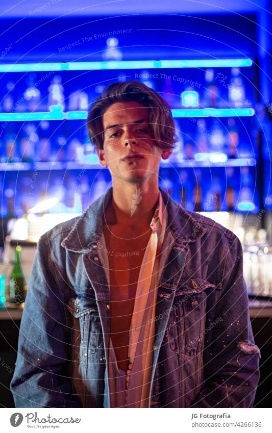 Porträt eines jungen Mannes in Jeansjacke mit Bar-Hintergrund. Model Aussehen weiß Freizeitkleidung Stehen Licht Seite Lächeln Junge Halt Gesicht hinten Person
