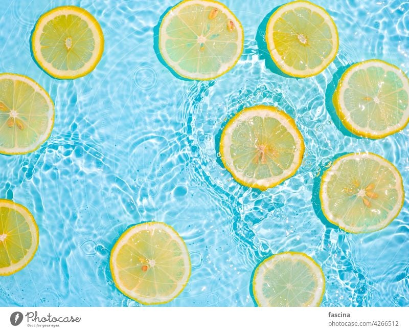 Zitronenscheiben in sauberem, transparentem Wasser, blau bg Zitrusfrüchte Sauberkeit gelb Geplätscher flache Verlegung Hintergrund copyscape Flachlegung