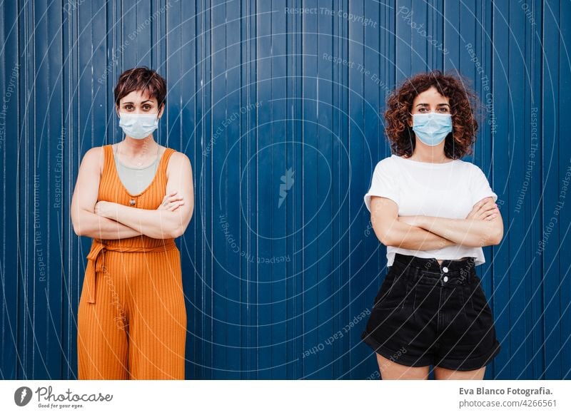 zwei kaukasische Frauen im Freien mit Gesichtsmaske, die während des Coronavirus soziale Distanz wahren Ellbogen COVID Kaukasier vermeiden Prävention Mundschutz