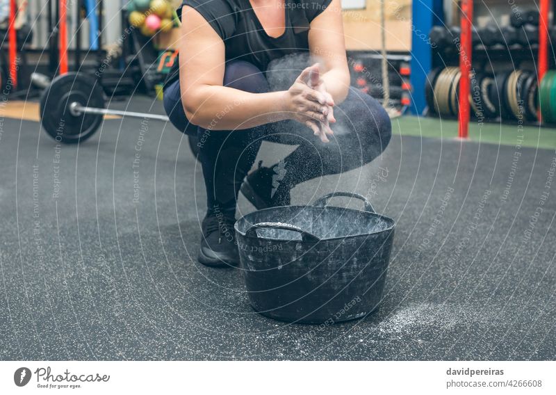 Unerkennbare Frau, die Magnesium anwendet, um Gewichtheben zu üben Hände Klatschen unkenntlich anwendend Setzen Sportlerin körperpositiv Pulver Cloud