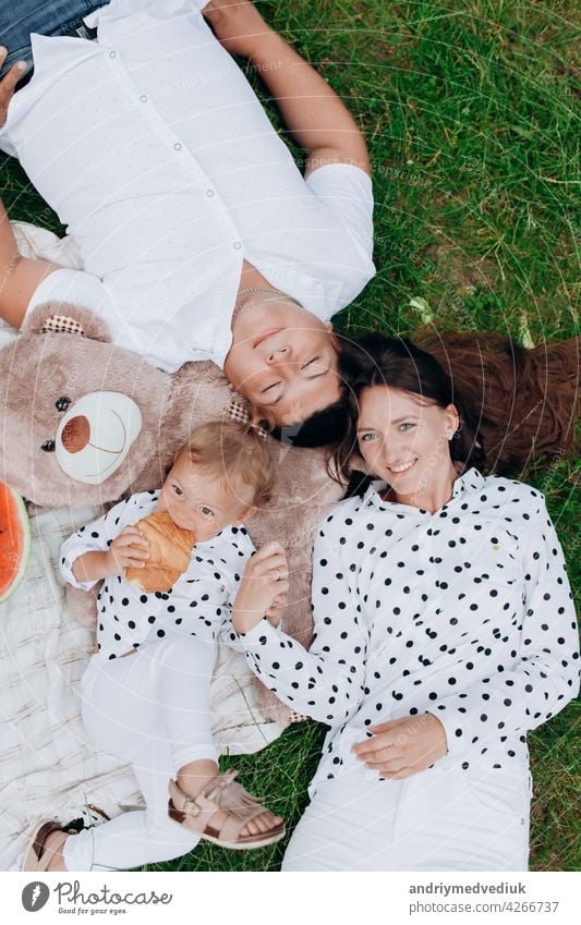 Mama, Papa und Tochter liegen auf dem Picknick mit Teddybär. Das Konzept der Sommerferien. Mutter, Vater, Baby-Tag. Familie verbringt Zeit zusammen in der Natur. Familie Blick