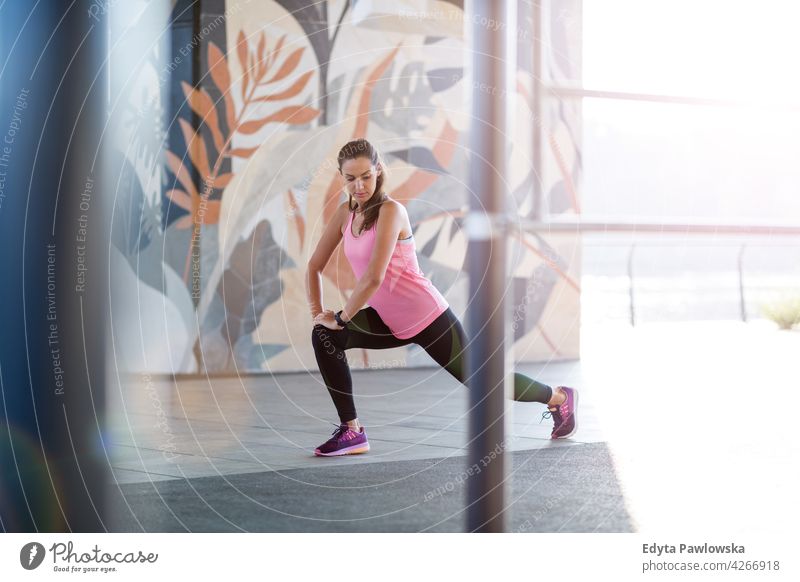 Junge Frau macht Fitness-Übung im städtischen Bereich Energie trainiert. Sport Aktivität Vitalität Körper Turnkleidung Training anstrengen beweglich