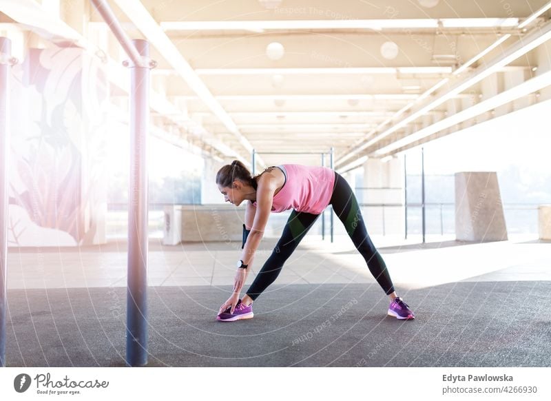 Junge Frau macht Fitness-Übung im städtischen Bereich Energie trainiert. Sport Aktivität Vitalität Körper Turnkleidung Training anstrengen beweglich