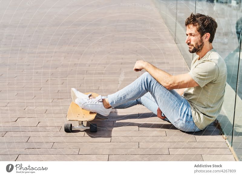 Ernster Mann lehnt an transparenter Absperrung an der Böschung Skateboard maskulin Kälte sich[Akk] entspannen cool Stauanlage Fluss Promenade Erholung männlich