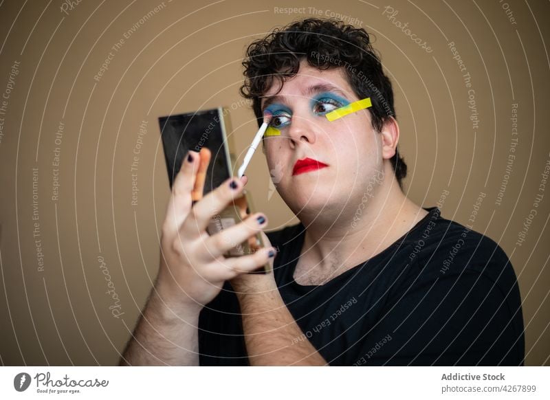Auftragen von leuchtendem Make-up auf die Augenlider eines queeren Mannes visagiste Bürste bewerben Gesicht Lidschatten Schönheit androgyn männlich Stylist