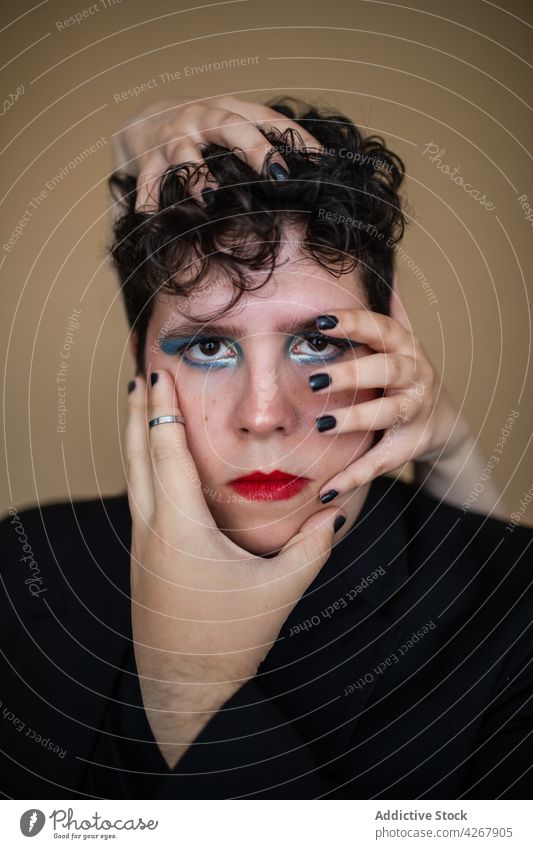 Androgyner Mann unter den Händen einer Frau, die das Gesicht berührt Make-up exzentrisch Stil feminin queer ungewöhnlich Transgender alternativ provokant