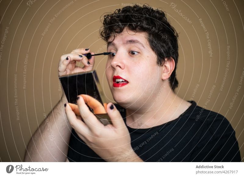 Androgyner Mann beim Auftragen von Wimperntusche während des Schminkens Stylist queer androgyn bewerben Schönheit Make-up Kosmetik Spiegel männlich Transgender