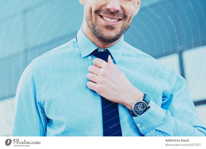 Geschäftsmann mit Armbanduhr in der Stadt mit Ernteertrag Exekutive gut gekleidet Inhalt unabhängig Stil Krawatte maskulin Großstadt Mann Lächeln Macho brutal