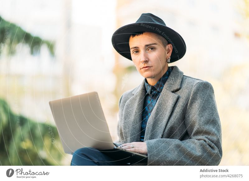 Transsexuelle Person beim Tippen auf einem Laptop in der Stadt androgyn Internet online Hut mohawk Identität benutzend Apparatur Gerät Netbook Transgender