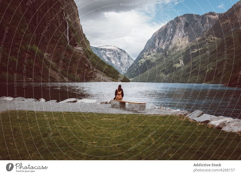 Tourist sitzt auf einer Bank am Ufer eines Bergsees Reisender See bewundern Berge u. Gebirge Hochland Berghang Kamm Fundstück Ambitus Ausflug Person Freiheit