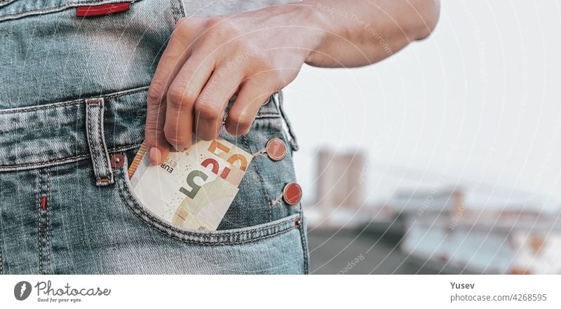WEB-Banner-Format. Eine Frauenhand nimmt einen Euro aus ihrer Jeanstasche. Das Konzept der Finanzen, Ersparnisse, finanzielle Ausgaben. Nahaufnahme. Kopierraum