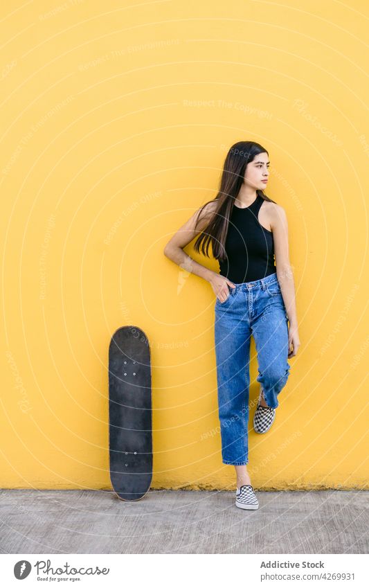 Skateboarder in Freizeitkleidung auf dem Bürgersteig auf gelbem Hintergrund Skater cool Zeitgenosse Generation freie Zeit Lifestyle Teenager Straßenbelag Gerät