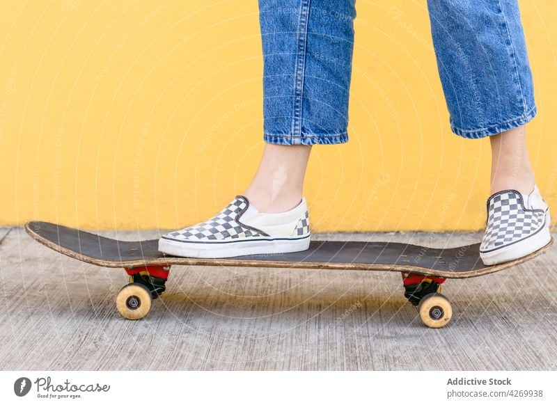 Anonymer Skateboarder in Freizeitkleidung auf dem Bürgersteig auf gelbem Hintergrund Skater cool Zeitgenosse Generation freie Zeit Lifestyle Teenager Gerät