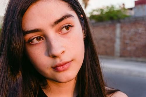 Teenager steht auf der Straße im Sonnenlicht besinnlich feminin sanft Angebot tausendjährig Schatten Porträt Profil nachdenklich Zeitgenosse Generation