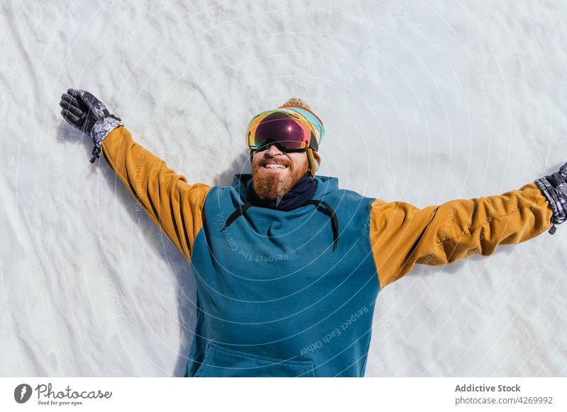 Lächelnder Sportler mit Schutzbrille, der sich im Winter im Schnee ausruht ruhen Hipster ausdehnen Freiheit brutal Mann froh heiter Athlet Handschuh herzlich