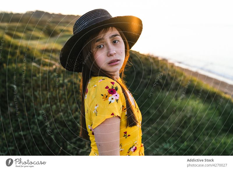Junge Frau steht auf einem Rasenstück Sonnenkleid Landschaft Natur verträumt Grasland Wiese grasbewachsen jung Feld Hut Vorschein Gelassenheit Anmut feminin