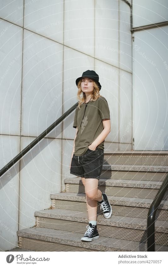 Millennial-Frau auf einer Treppe gegen eine Betonwand in der Stadt Individualität Stil lässig feminin sanft Lifestyle urban Angebot romantisch wehmütig