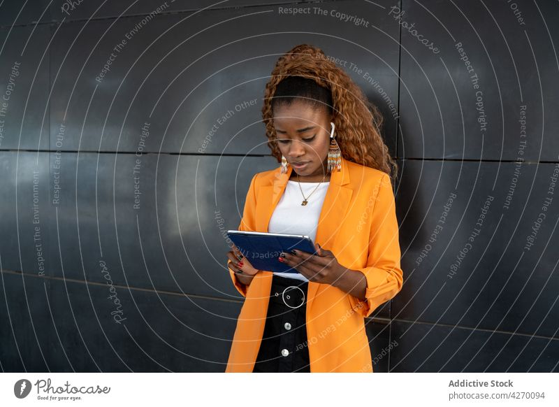 Seriöse schwarze Frau, die in der Passage auf einem Tablet surft benutzend Tablette online Internet Stil zuschauen Fokus digital Gang Browsen Gerät Surfen