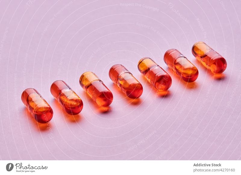 Orangefarbene Pillen auf rosa Oberfläche Tablette Medikament Kapsel Kur Zusammensetzung orange Abhilfe Vitamin Leckerbissen Apotheke Gesundheitswesen Konzept